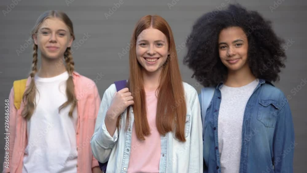 Female teenagers with school bags smiling each other, student exchange program
