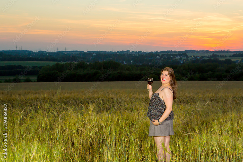 Lady celebrates outdoors with wine in the country side during twilight