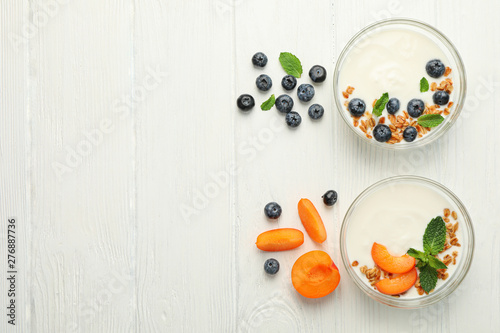 Flat lay composition with yogurt desserts and ingredients on white wooden background