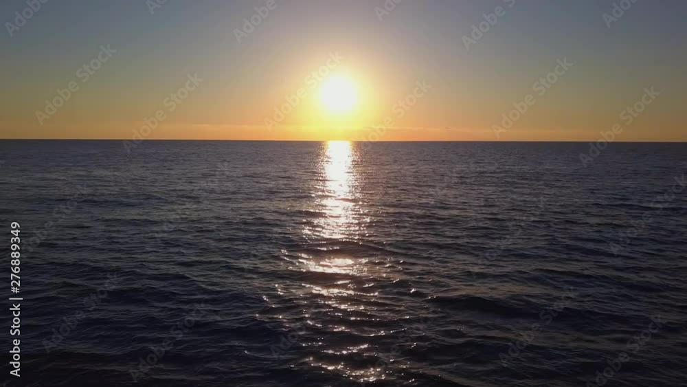 Aerial view of drone slide over sea surface in sun light, golden hour sunset. Cinematic shot panorama camera flies from right to left above ocean waves, sun on horizon, clear sky Aerial view of drone slide over sea surface in sun light, golden hour sunset. Cinematic shot panorama camera flies from right to left above ocean waves, sun on horizon, clear sky