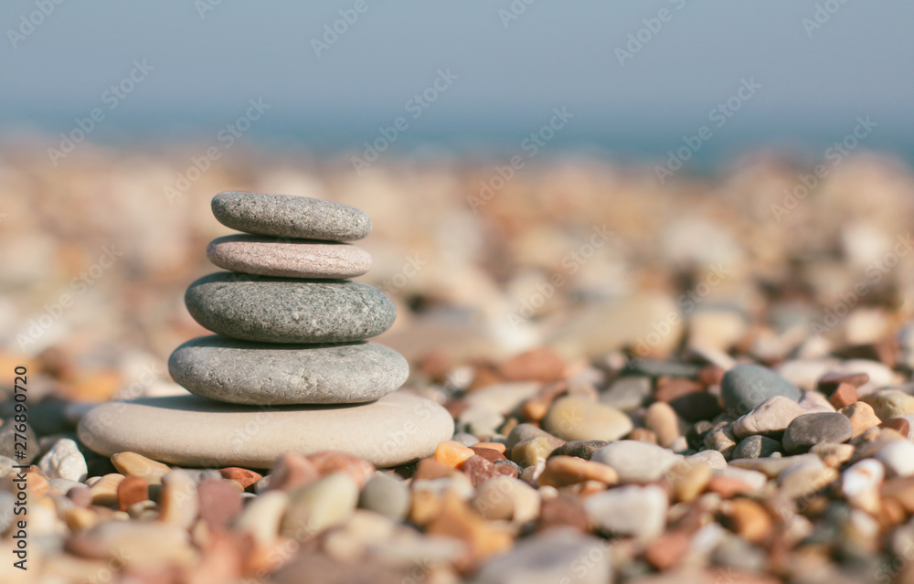 Stone zen pyramid on blurred beach background. Warm summer photo. Calm and rest place. Spa therapy background. Text space.