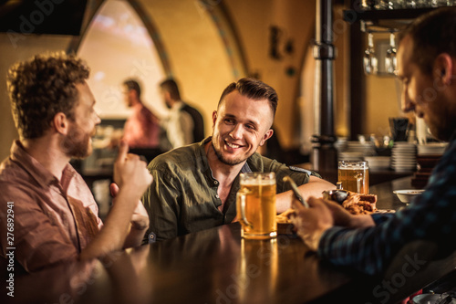 Cheerful friends drinking draft beer in a pub
