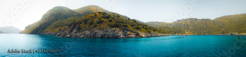 Secluded mountain coastline in a tranquil bay with turquoise water at sunrise, Oludeniz, Turkey panoramic