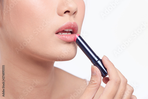 Pretty asian woman applying lipstick, isolated on white © makistock