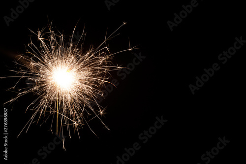 One small new year sparkler on black background.