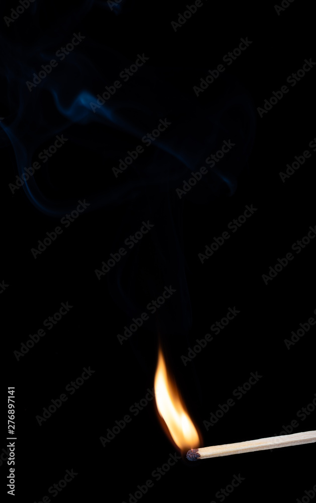 Burning wooden match with smoke over black background. Copy space Burning wooden match with smoke over black background. Copy space