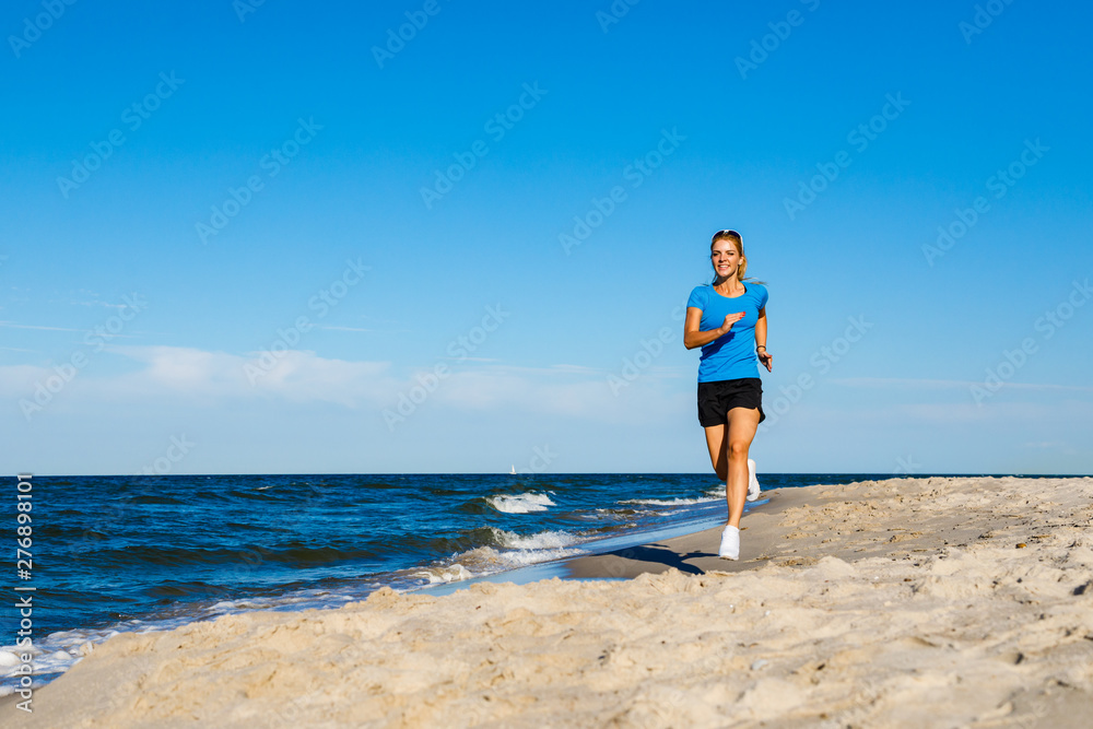 Young woman running, jumping on beach