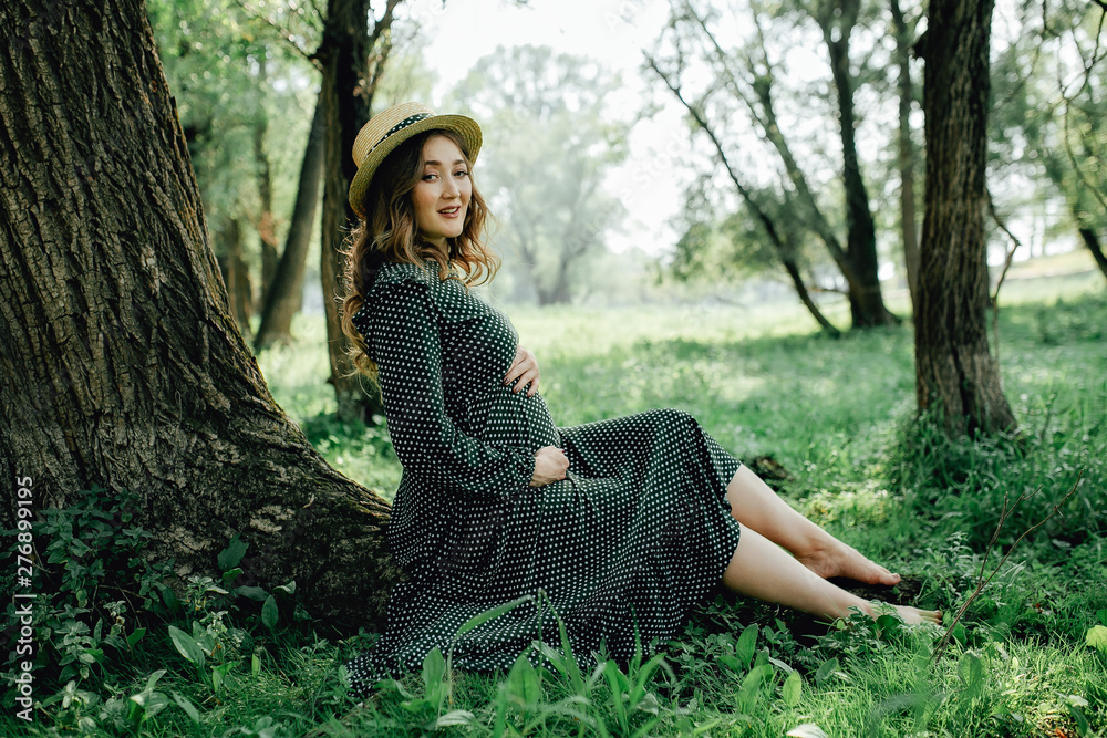 Obraz premium Young pregnant woman relaxing in park outdoors