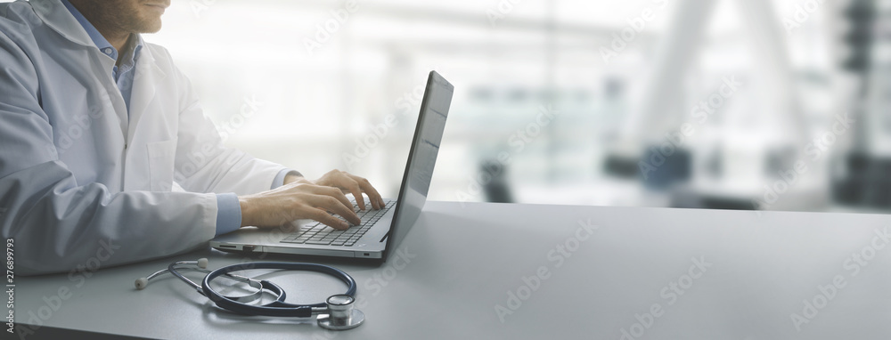 doctor working on laptop computer in modern clinics office. copy space - obrazy, fototapety, plakaty 