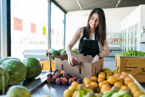 Female Owner Displaying Fresh Peaches In Shop