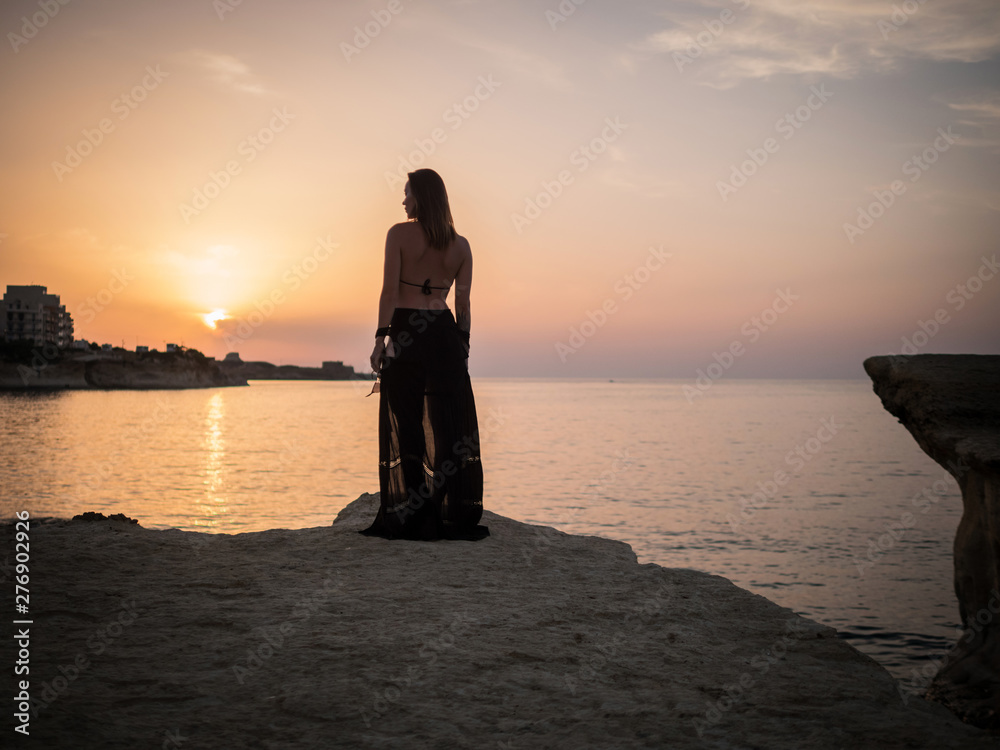 Woman looking on a resort town at dusk - obrazy, fototapety, plakaty 