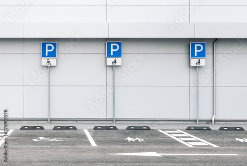 Empty car parking lot at a supermarket with family and disability parking places, public parking road signs 