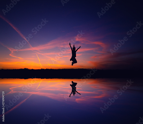 silhouette of a woman jumping on the beach at sunset