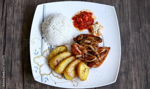 African fried chicken with fried bananas, rice, fried onions, chili sauce and candlenut sauce.