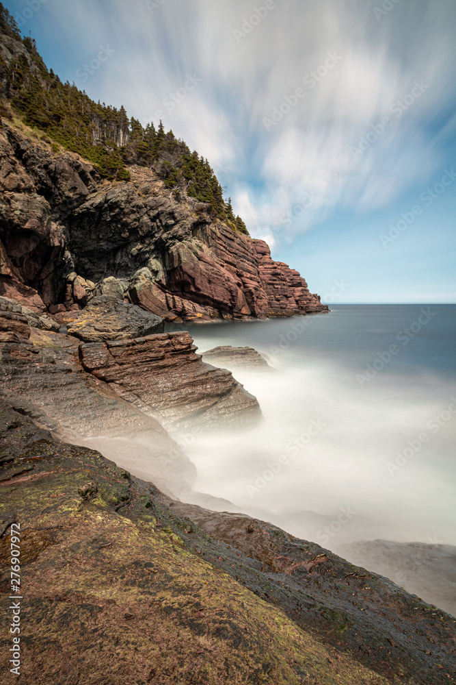 Dramatic seascape with silky smoothed out ethereal water meeting a rocky coast line. 