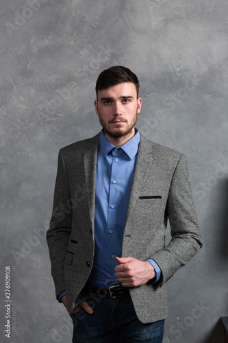 Handsome stylish young man standing in interior on gray background