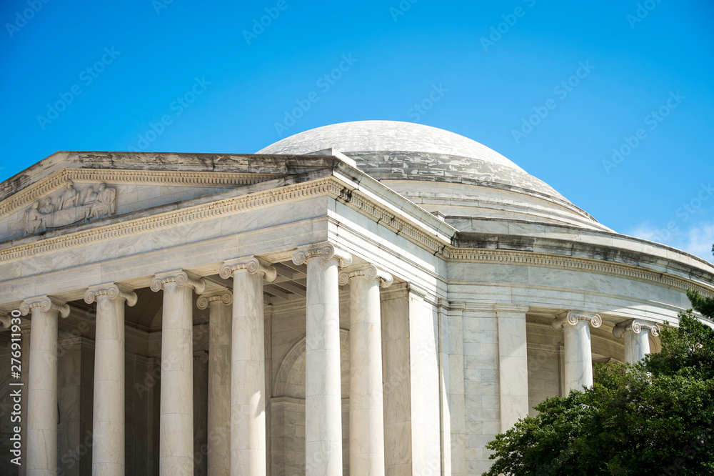 Scenic view of white marble neoclassical columns decorating the exterior of the Jefferson Memorial on a bright summer day in Washington DC, USA