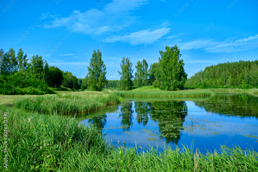 Obraz premium Sunny summer landscape with river. Green hills and meadows. Fields of lush green grass.