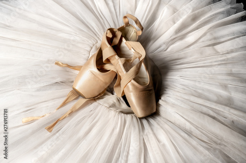 Pointe shoes. Peach shoes, ballet shoes with ribbons on a white tutu in a dance studio. Advertising ballet school. Professional ballerina outfit. photo
