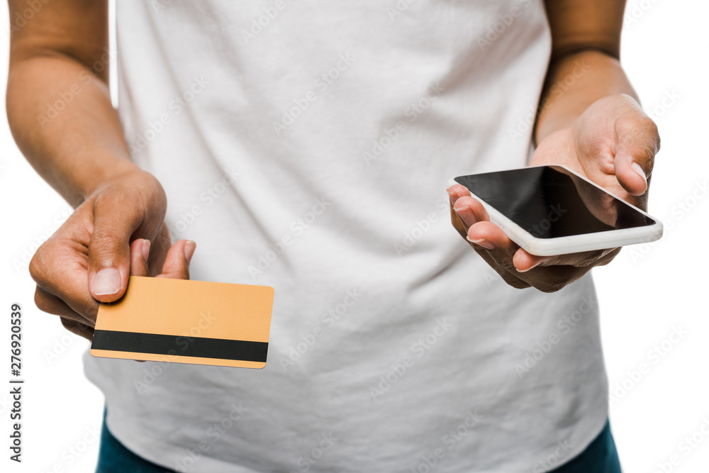 cropped view of african american woman holding credit card near smartphone with blank screen isolated on white cropped view of african american woman holding credit card near smartphone with blank screen isolated on white