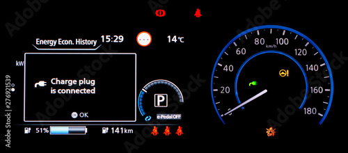 Electric car dashboard panel during charging battery. Modern digital car display showing warning text about connecting charge plug and the battery range.