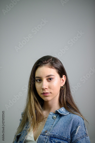 Young caucasian girl with brown hair posing on grey background © frimufilms