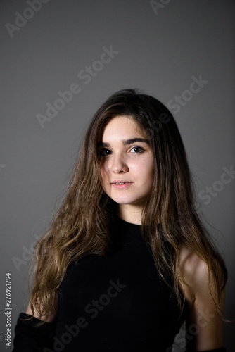 Young caucasian girl with brown hair posing on grey background