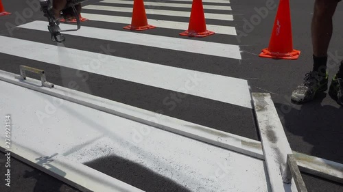 Worker is painting a pedestrian crosswalk.
