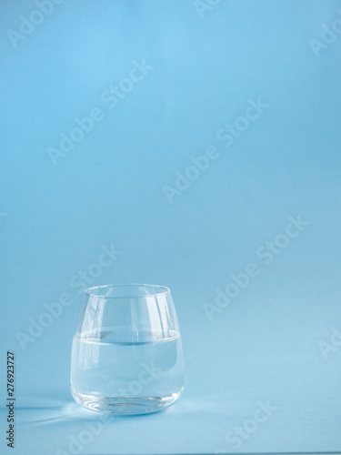 a glass of plain water on a blue background © Юлия Зажигалина