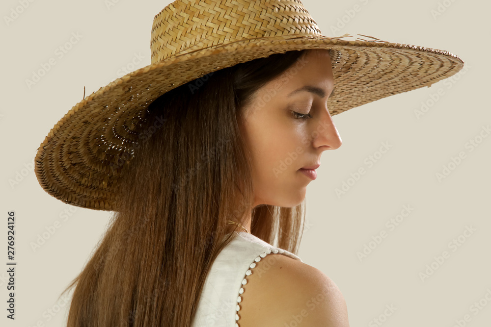 Studio portrait of a young brunette wearing wide brim straw hat 