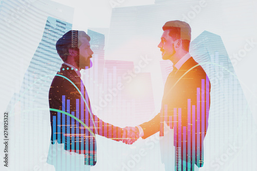 Businessmen shaking hands in city, graphs
