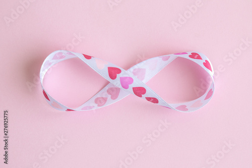 Endless love abstract made of ribbon with hearts in form of infinity sign isolated on rose.