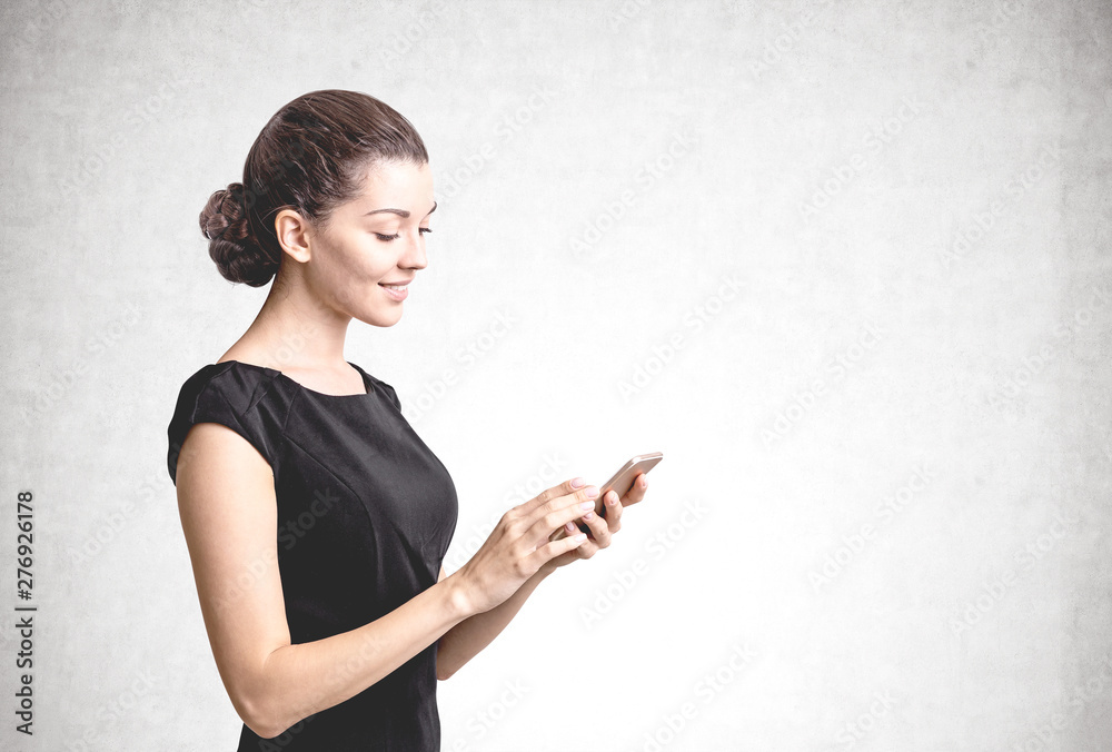 Smiling woman using phone, concrete wall Smiling woman using phone, concrete wall