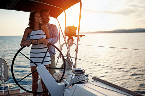 Romantic couple sailing on the luxury boat together and enjoy at sunset.