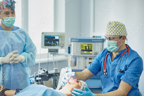 Several doctors surrounding patient on operation table during t