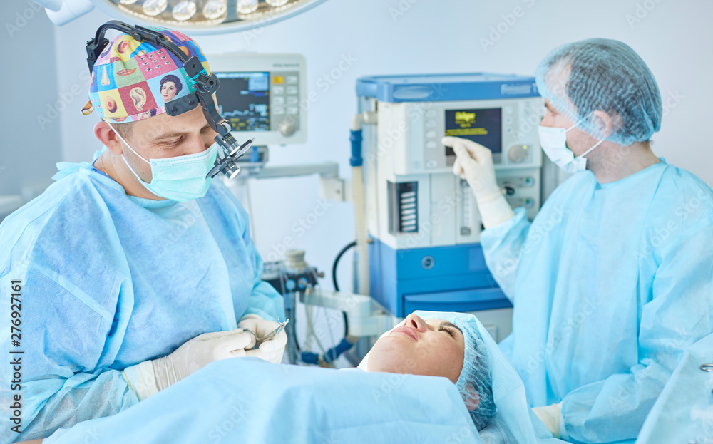 Several doctors surrounding patient on operation table during t Several doctors surrounding patient on operation table during t