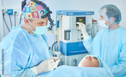 Several doctors surrounding patient on operation table during t