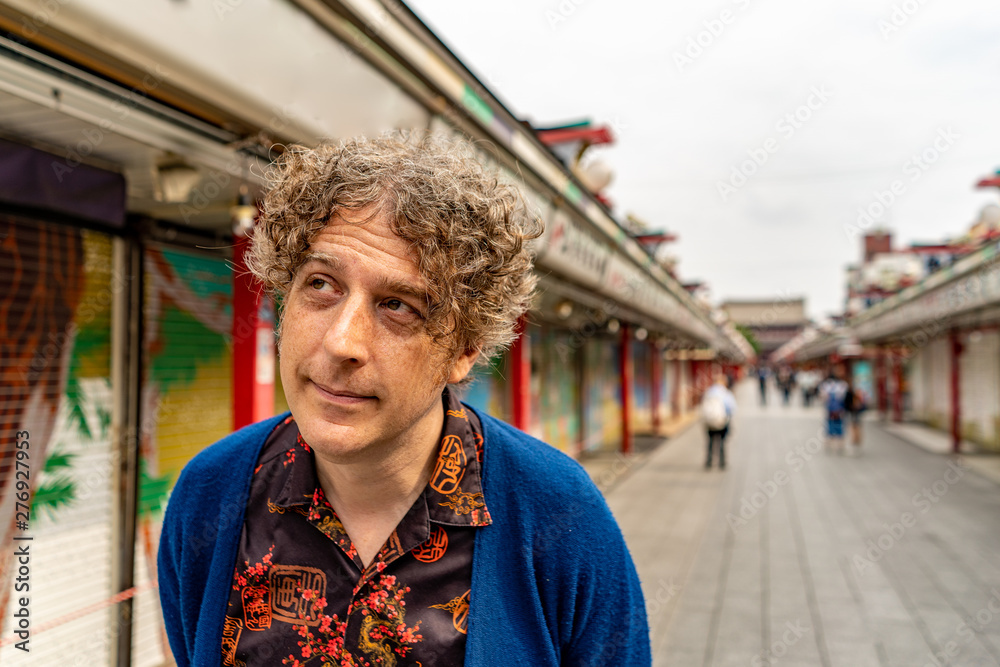 An attractive man poses while exploring romantic Nakamise Street Market at the historic Senso Ji Temple in Asakusa, Tokyo, Japan. An attractive man poses while exploring romantic Nakamise Street Market at the historic Senso Ji Temple in Asakusa, Tokyo, Japan.