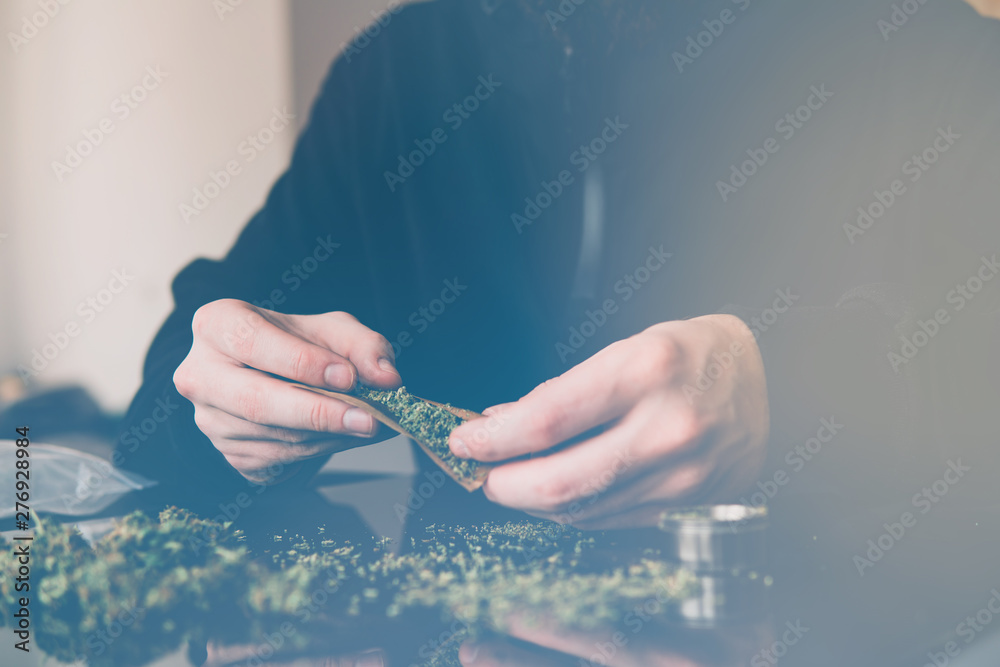 Close up marijuana joint with lighter. Man rolling a marijuana weed blunt.  Man rolling marijuana cannabis blunt. light licks color toned light leaks  Stock Photo | Adobe Stock