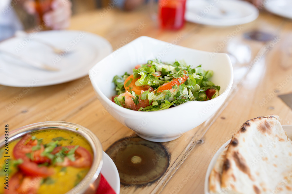 food, south asian cuisine, culinary and cooking concept - vegetable salad in bowl on table at indian restaurant