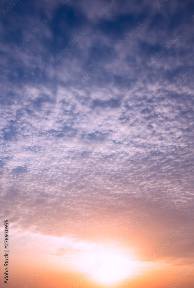 Fototapeta premium Bright sun at sunset on the background of clouds and blue sky.