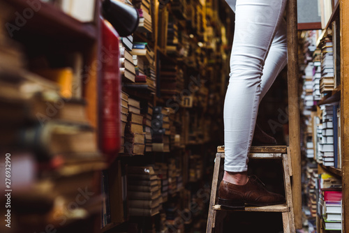 selective focus of woman standing on wooden ladder in library