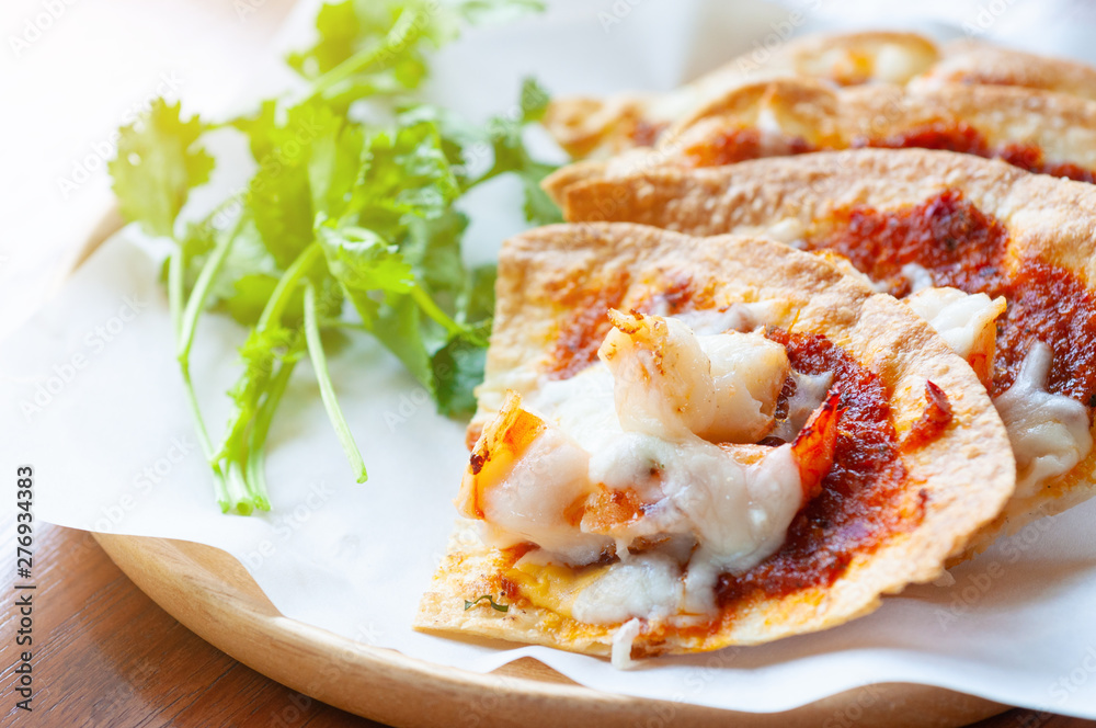 Set of crispy shrimp baked with chilli sauce and vegetable on paper and Thai parsley in wooden dish.