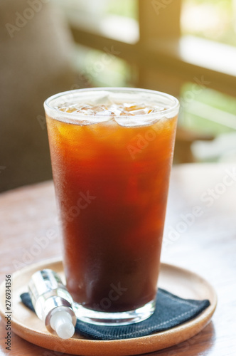 Coffee ice americano with additional syrup bottle for customer.  Ice black tea in high glass with canvas coaster.