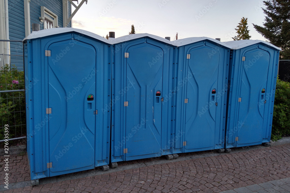 Four blue portable toilets. Copy space. Four blue portable toilets. Copy space.