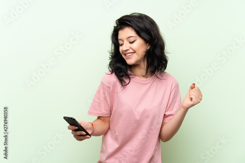 Young woman over isolated green background surprised and sending a message