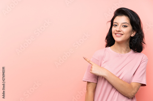 Young woman over isolated pink background pointing finger to the side