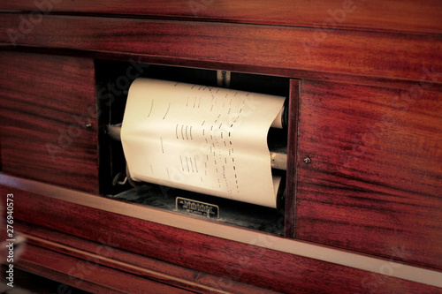 A vintage automatic player piano (with an inner mechanism reading self-playing scores), close-up detail shot of the musical sheet.