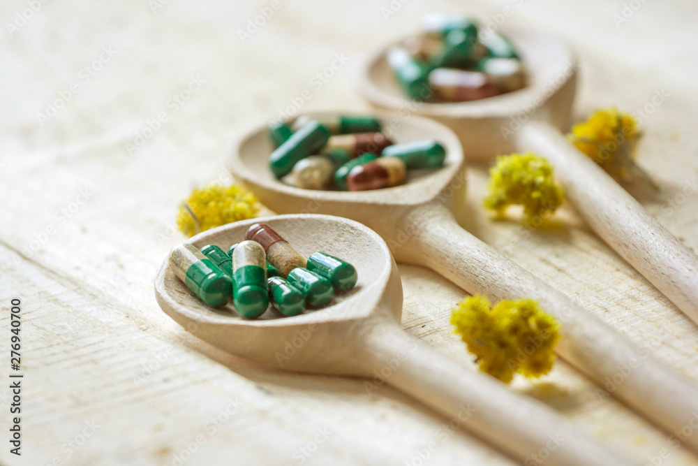 Herbal pills on wooden spoons. Chamomile and mint leaves. Medicinal herbs. Herbal pills on wooden spoons. Chamomile and mint leaves. Medicinal herbs.