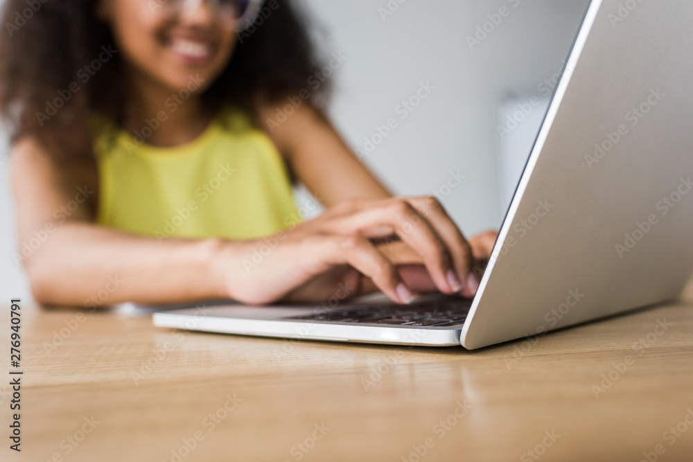 selective focus of happy african american woman using laptop